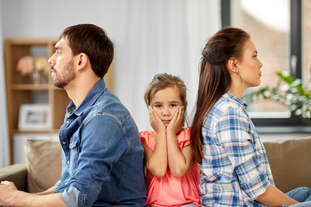 親の不仲に戸惑う女の子と、背を向ける両親のイメージ。家庭内の問題や葛藤の中で不安を感じている様子
