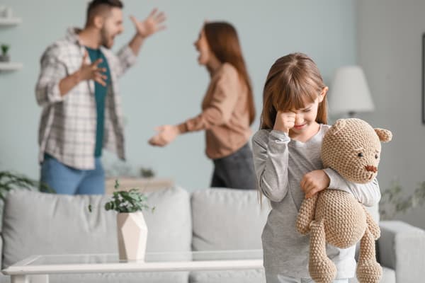 喧嘩している両親と、不安そうにぬいぐるみを抱く女の子の様子
