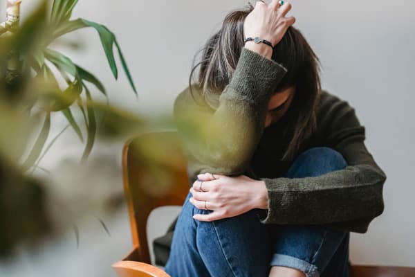 悲しみや孤独を感じている女性が、部屋の中でうずくまっている様子