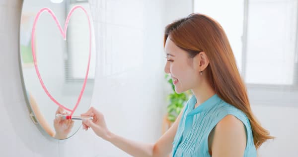 鏡にハートを描きながら微笑む女性。自己肯定感やセルフラブのイメージ
